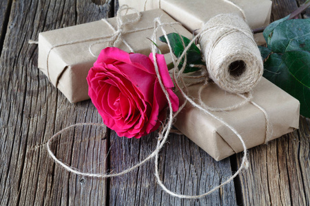 一朵红玫瑰和礼品盒用丝带与副本空间仿古木制的桌子上