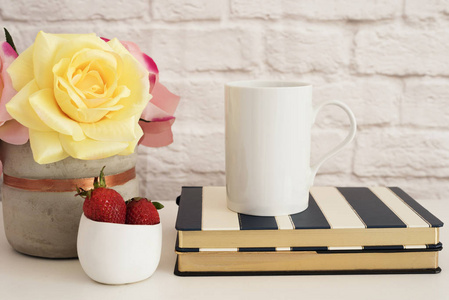 咖啡杯产品显示。对条纹的设计笔记本的咖啡杯。草莓在金碗里，用粉红玫瑰的花瓶
