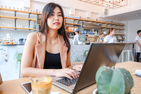 亚洲商业女性使用笔记本电脑在现代咖啡店, 休闲自由的妇女