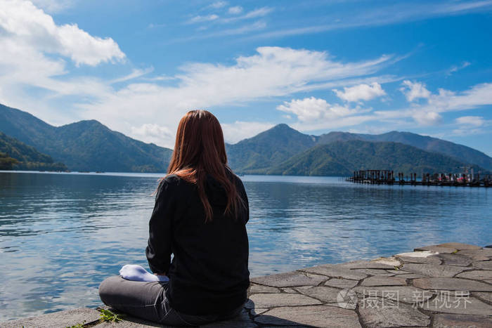 一个女人坐着独自湖和蓝蓝的天空背景