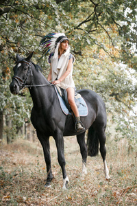 年轻女子和黑色的马在森林里的肖像