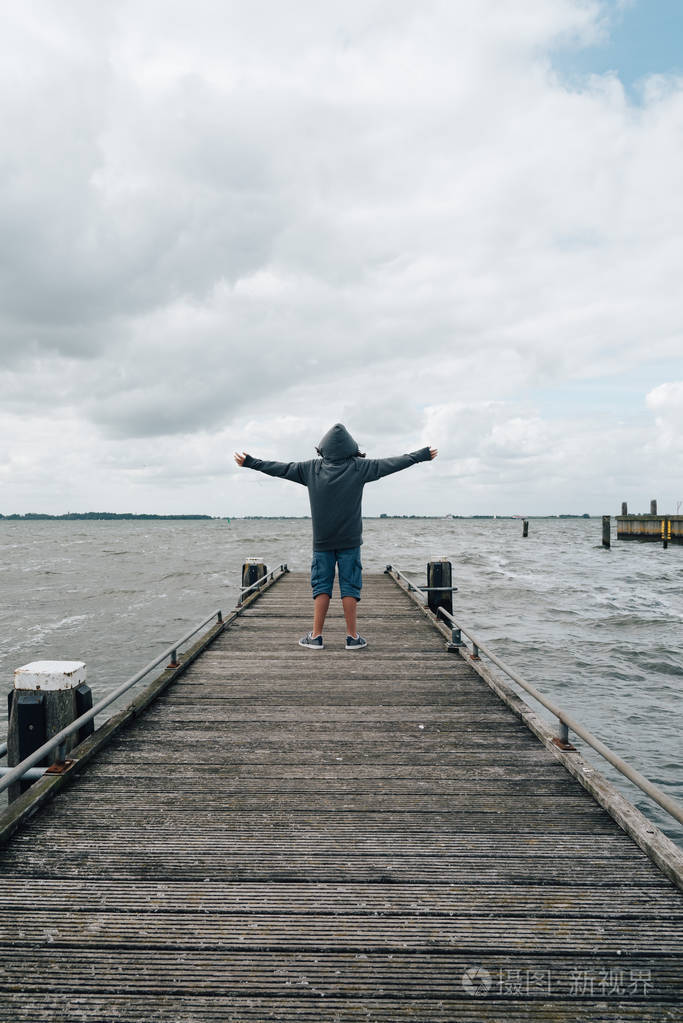照片 人物 后面的观点的木码头上穿连帽衫的张开双臂的女孩.jpg