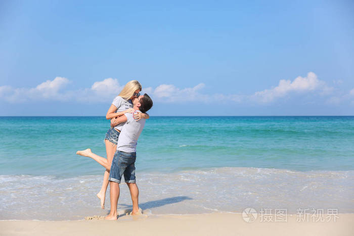 幸福小两口微笑控股在彼此附近的海滩上.爱情故事