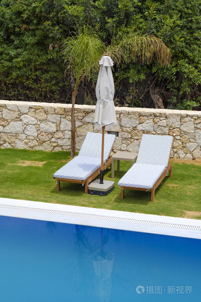 站在游泳池旁的两个日光浴浴床