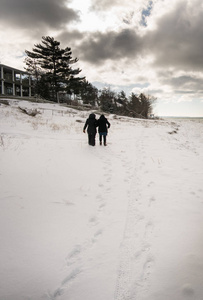 两人走上坡，在白雪覆盖的风景