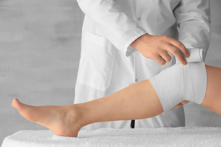 医生应用到临床病人的腿上的绷带照片