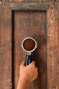 新磨碎的咖啡豆在金属过滤器手上