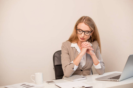 严重的女人坐在办公室中的表和业务战略的思考
