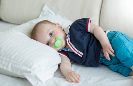 可爱的小宝贝男孩用安抚奶嘴躺在床上的肖像