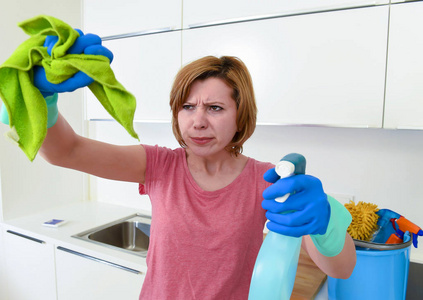 女人在自家厨房手套举行清洁擦和洗涤剂喷雾瓶用布擦