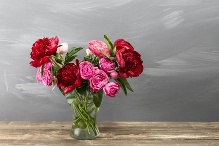 红牡丹和玫瑰插在花瓶里。复古风格的照片。特写