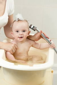 开朗的小男孩正在洗澡，玩淋浴头