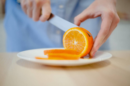 一个女人握着一把刀，削减橙色