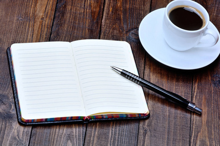 用钢笔和咖啡杯子在桌上的笔记本