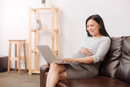 微笑孕妇使用一台笔记本电脑