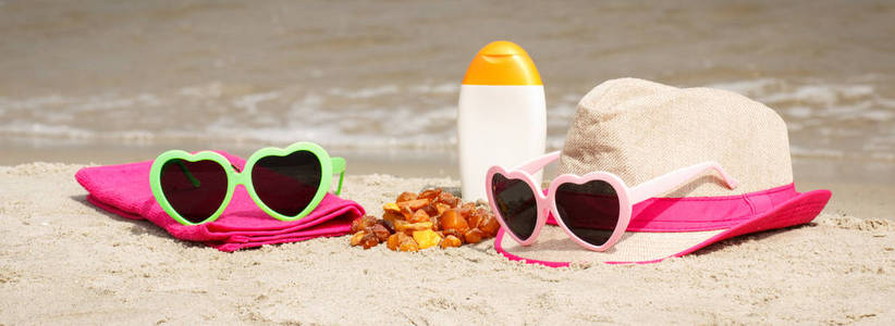 琥珀色的石头和配件的度假或夏天在海滩，太阳保护的概念