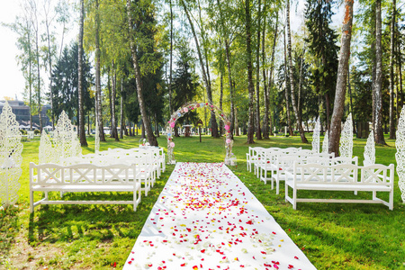 美丽的花拱为婚礼仪式的。由弯杆与绣球花和玫瑰。在公园的户外婚礼设置