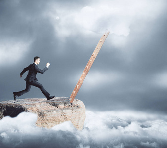 年轻的商人的山顶级奔向梯子上沉闷的天空背景上的侧面图.