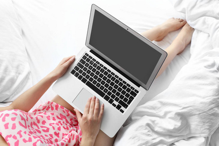 年轻的女人在床上使用笔记本电脑