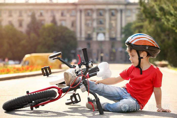 逗人喜爱的小男孩从他的自行车跌倒了室外