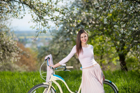 骑单车与复古自行车春天的花园里的美丽女子