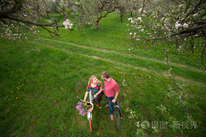 恩爱的小夫妻与自行车在春天的花园