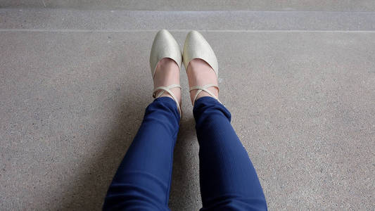 在高的女人腿跟金色凉鞋站在地上,室外背景照片