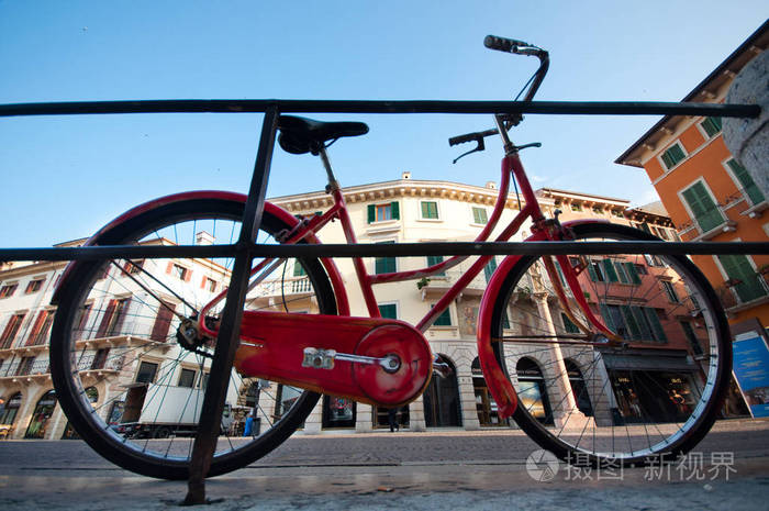 老式红色自行车躺在围栏上, 在维罗纳, 意大利