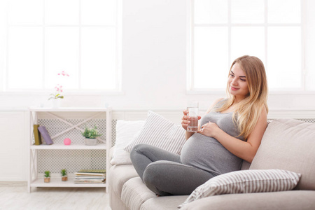 杯水，坐在沙发上的孕妇