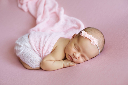 新出生的婴儿，穿着一件粉红色的头巾和兔兔