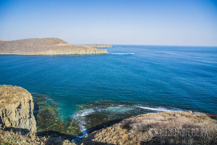 力量的磐石,折叠在蓝色的大海,与太阳眩光,雄伟壮观的岩石