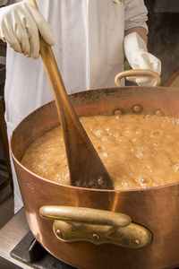 用温度计和大匙沸腾铜锅糖的糖浆。由于蒸发的棕色颜色