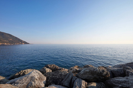 用石块和海岸，晴朗的天空在意大利地中海蓝色，平静的海面