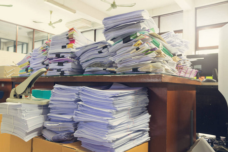 文档的工作量，未完成的文件在办公室桌上，堆栈的商务用纸，老式影响桩的概念