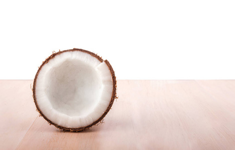 浅木背景上的新鲜椰子。上轻木桌前，在白色背景上孤立的热带椰子。新鲜的营养椰子切成两半