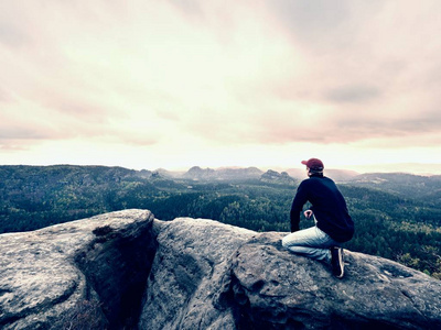 男子旅游坐在山顶上。旅行的山景。徒步旅行者休息独自在山上