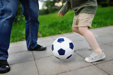 小男孩与他的父亲在阳光灿烂的夏天一天玩足球游戏的乐趣