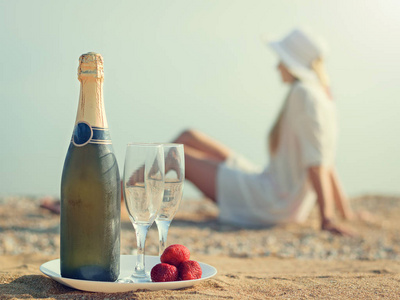 一瓶香槟 眼镜 草莓和在沙子里的女人