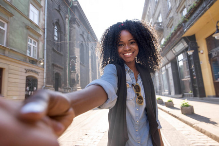 快乐的黑人女孩握着手, 摆着相机。一个阳光明媚的日子, 女孩 aroung 地漫步在城市