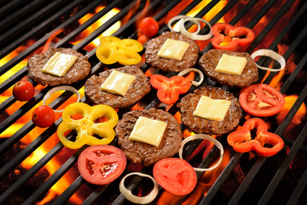 用奶酪和蔬菜火红的烤架上烤的肉汉堡