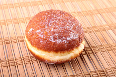 自制甜甜圈配果冻填充和竹桌布上的糖粉。选择性的焦点