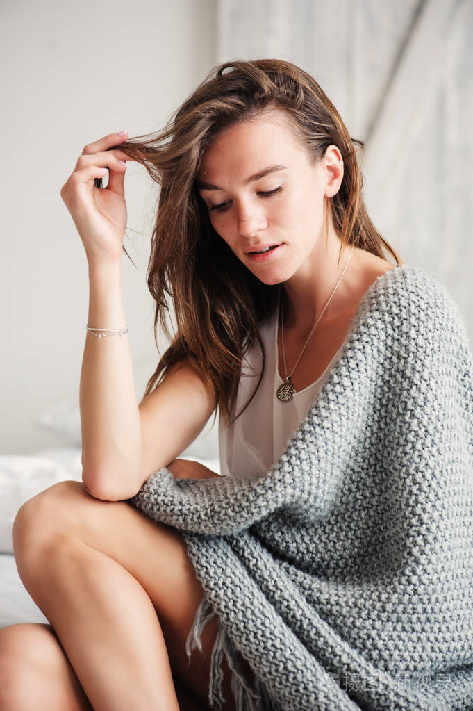 年轻性感的女人轻松在家躺在床上在周末的早晨,针织毯裹.