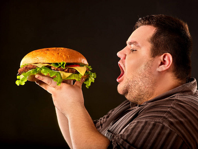胖子吃快餐汉堡。早餐为超重的人的