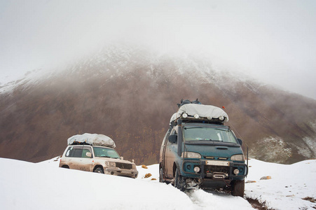 两辆车的旅行者在山雪道路景观。在一座山的 4  4 吉普车车通过，登上峰顶。极端危险的冒险