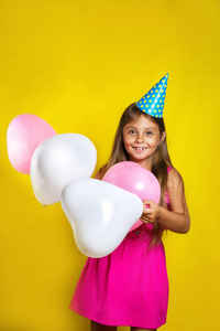 画室肖像，一个小女孩在她生日那天穿党的帽子。五颜六色的气球快乐的女孩