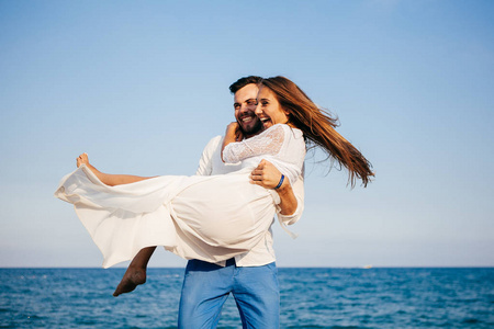 小两口沙滩幸福的小两口爱拥抱,拥抱微笑着在沙滩上照片