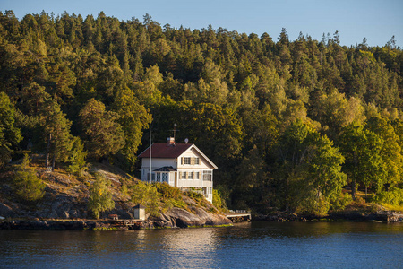 查看在瑞典斯德哥尔摩群岛沿森林小屋。夏季日落时间