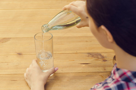 年轻漂亮的女人,在休闲衬衫倒水入杯照片