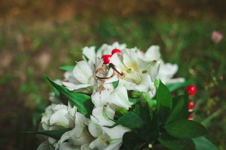 美丽的金色结婚戒指与婚礼花束新娘在绿草夏季特写