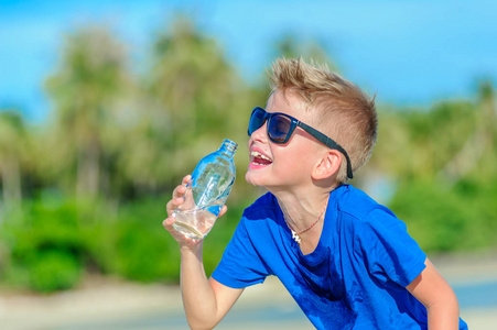 口渴的英俊的男孩太阳镜饮用水中的肖像